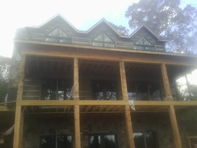 Dormers and porch framing on a large log home under construction — Roof Coating work by our crew in Fawn Grove