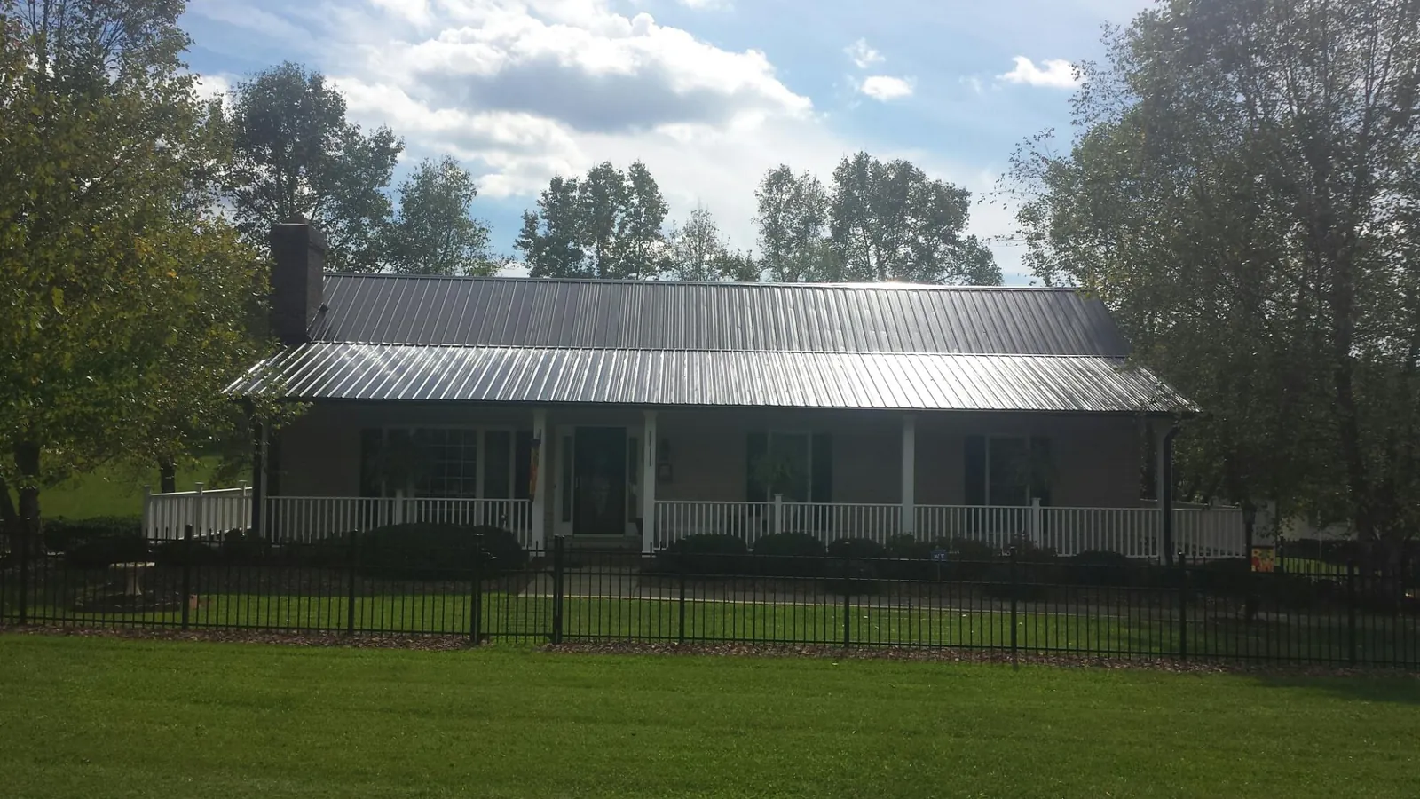 Gray metal roof on a brick ranch with a full width front porch — Gutter Guard Installation work by our crew in Fawn Grove