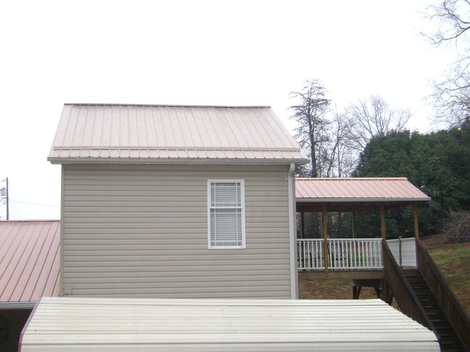 Tan metal roofs on a two story addition and attached porch, from a Roof Replacement job in Fawn Grove