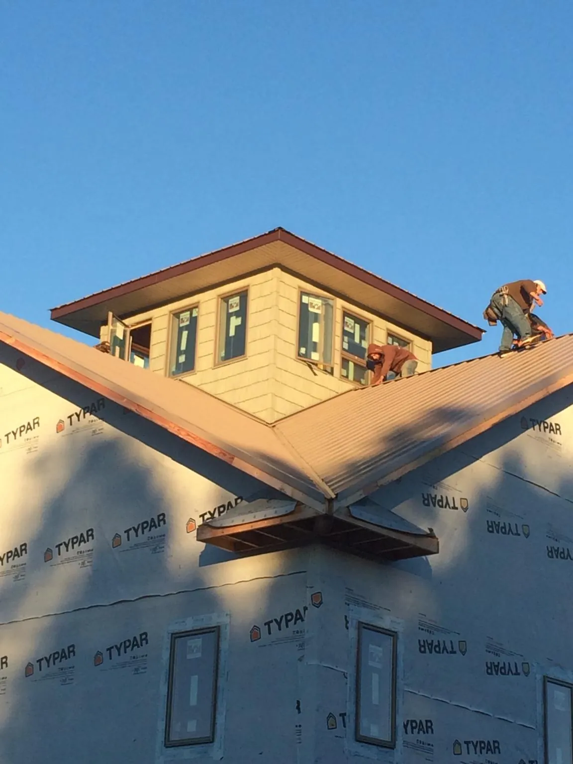 Roofers working around a rooftop cupola on a new metal roof at sunset — Roof Waterproofing in Fawn Grove by Roofing Brothers